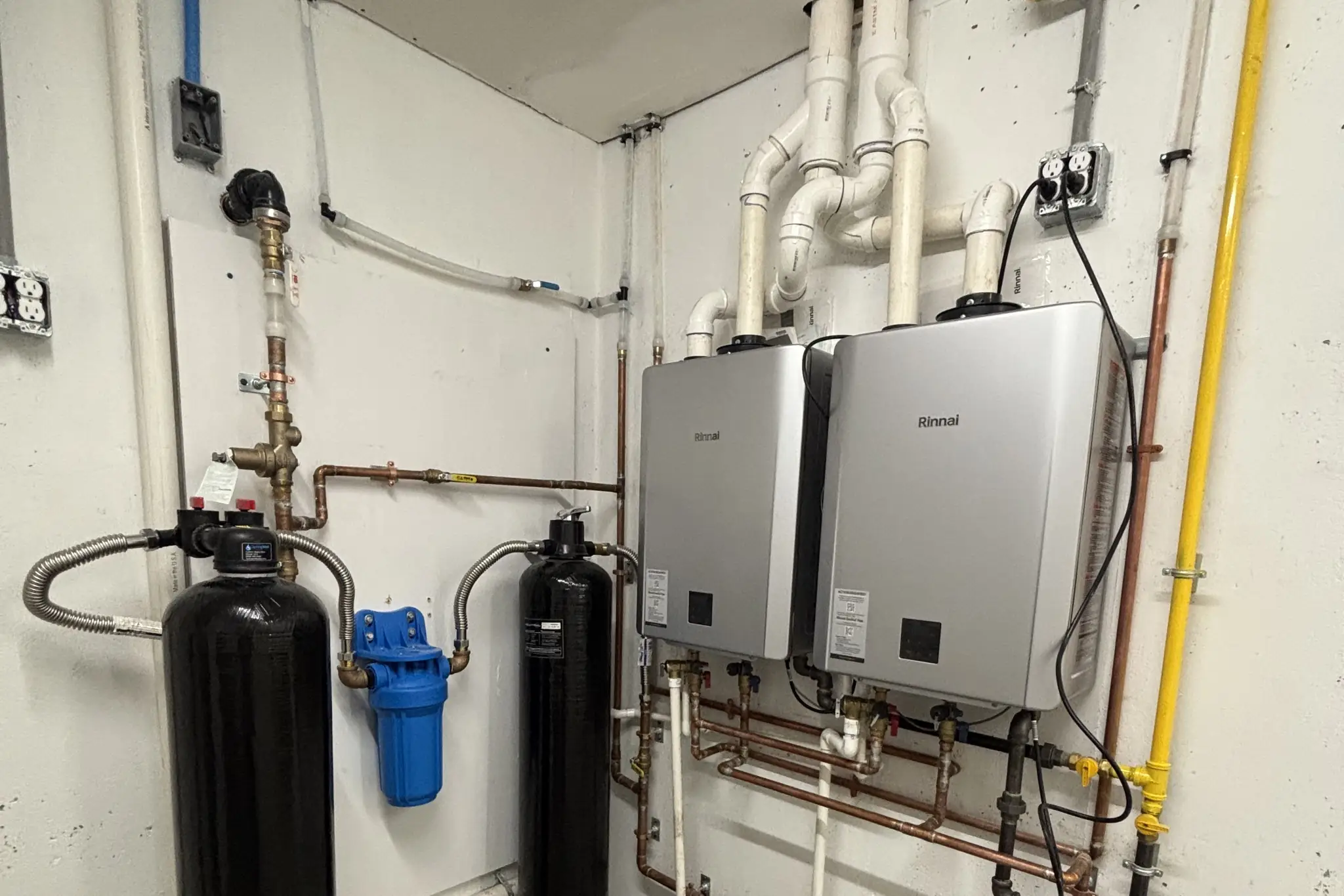Two tankless water heaters installed side by side with water treatment